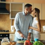 Happy young couple in the kitchen. Handsome man meet and kiss his girlfriend early morning at home