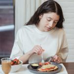 Woman having a nutritious breakfast with toast and strawberries in a cozy indoor setting.