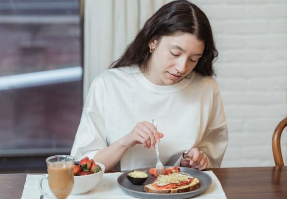 Woman having a nutritious breakfast with toast and strawberries in a cozy indoor setting.
