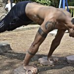 Athletic man performing elevated push-ups on rocks in a park setting.